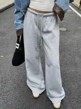 Light gray wide leg drawstring sweatpants with a loose fit, cuffed hems, and a drawstring waistband with care instructions