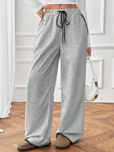 Gray wide-leg pants with black drawstring and zigzag trim designed for comfort and machine wash care instructions