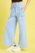 Light blue umgee drawstring wide leg pants with scallop trim detail and embroidered green and white pocket accents