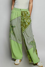 Green patchwork wide-leg pants with floral and striped fabric panels featuring partial elastic and big star patch