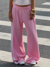 Pink wide leg pants featuring white side stripes made from soft sweatpant material for casual wear