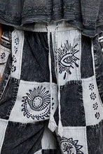 Black and white patchwork jogger pants in soft cotton fabric with embroidered eye and sun motifs