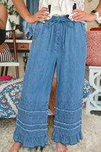 Blue chambray pants with wide leg silhouette and ruffled hem featuring a drawstring waist for adjustable fit
