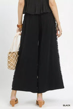 Black linen wide leg pants with frayed hem detail and side pockets featuring a relaxed fit design