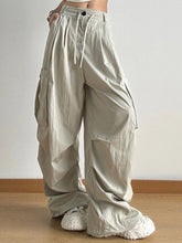 Drawstring wide leg cargo pants in loose beige fabric with multiple large pockets and an adjustable waistband