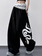 Black wide leg drawstring pants with bold white snake graphic star accents and sheer lace waistband in sweatpant material