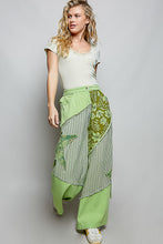 Green patchwork wide-leg pants with partial elastic waist and big star patch featuring striped and floral panels