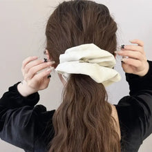 Cream-colored faux leather elastic hair scrunchy with black cross design