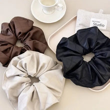 Three faux leather elastic hair scrunchies in brown, black, beige