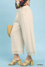 Cream-colored umgee linen wide leg cropped pants with delicate lace trim at the hem for an elegant look