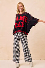 Black oversized sweatshirt with bold red game day lettering and trim paired with bibi gameday checkered printed pants