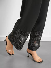 Black wide-leg trousers with floral lace hem featuring delicate white embroidery on a sheer lace hem wide design