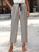Black and cream vertical striped high-waisted cropped pants with wide-leg design and drawstring waistband