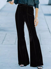 High-waisted wide leg velvet pants in black with subtle vertical seam detailing and flare design
