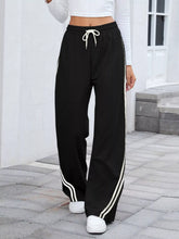 Black striped wide leg pants with white side stripes and matching drawstring waistband for casual wear