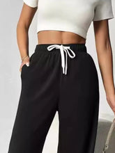 Black high-waisted wide leg pants with a white drawstring made from comfortable sweatpant material