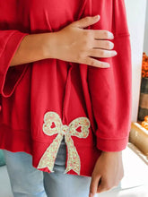 Red baggy sweatshirt with floral bow appliqué and exposed seam patchwork designed for machine wash cold care