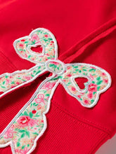A vibrant red floral bow patched exposed seam baggy sweatshirt featuring pink green blossoms wash cold