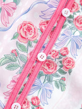 Floral collared ruffled half sleeve shirt in pink fabric with white buttons and matching pink stitching featuring lavender floral pattern
