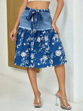 Blue floral denim skirt with white pattern, matching tie belt, and frayed hem detail for casual wear