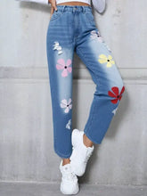 Light-wash denim jeans with colorful pink yellow and red floral embroidery and distressed ripped details