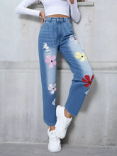 Light-wash denim high waist jeans with colorful pink yellow red floral embroidery and distressed white frayed patches
