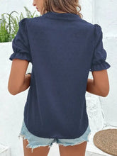 Navy blue short-sleeved blouse with textured dot pattern and ruffled cuffs featuring floral embroidered puff sleeves
