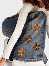 Blue denim jacket with golden floral embroidery paired with floral embroidered wide leg jeans in blue denim