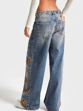 Wide leg denim jeans in faded blue wash with orange floral embroidery along the outer seam floral embroidered wide