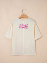 White half sleeve oversized t-shirt with vibrant floral patch on the back in a floral half sleeve design