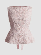 A blush pink floral jacquard peplum tank with delicate lace, structured floral pattern, and subtle back tie detail