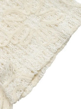Off-white knitted scarf with intricate raised floral patterns and soft weave paired with floral lace tie-front shirt