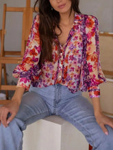 Floral print button up shirt with vibrant pink purple orange hues and ruffled puffy sleeves on lightweight fabric