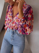Floral print button up shirt with vibrant pink purple orange hues, lightweight fabric, v-neckline, and puffy sleeves