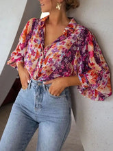 A floral print button up shirt with puffy sleeves in bold purple pink orange and white on lightweight fabric