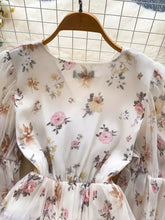 A delicate white floral print chiffon blouse with soft pink and beige blossoms and sheer puffy balloon sleeves