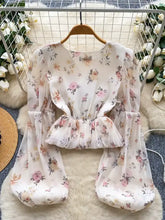 A delicate white chiffon floral print blouse with long puffy balloon sleeves and a ruffled waistband