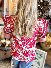 Red and white floral print blouse with flutter sleeves and burgundy lace trim featuring a v neck design