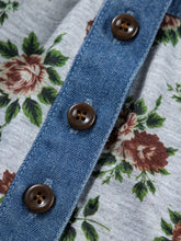 Brown matte four-hole buttons on denim strip detail a floral print denim patchwork blouse with light gray fabric