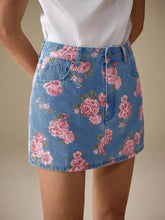 Denim skirt with vibrant pink rose floral print and green leaves on medium-wash blue background floral print denim skirt