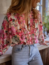 A flowing long-sleeved floral print frill trim blouse in shades of pink and peach on a light background