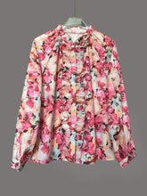 A long-sleeved blouse with floral print frill trim in pink peach and cream featuring ruffled detailing on front placket and neckline