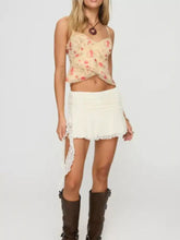 A cream-colored floral print lace trim cami with thin spaghetti straps and a ruffled hemline crop top