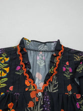 Black floral print short sleeve shirt with frilled v neck and vibrant orange beaded trim along the neckline and sleeves