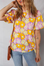 A vibrant floral print puff blouse with ruffled short sleeves in shades of yellow pink and purple
