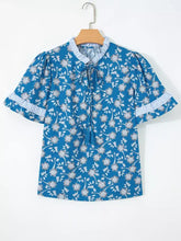 Blue floral print blouse with white and light blue striped ruffled cuffs collar and tie-front detail