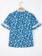 Blue floral print blouse with white and gray pattern featuring ruffled sleeves trimmed in blue and white stripes