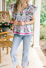 A woman wearing a light blue and pink floral print ruffle sleeve blouse with gathered waistband and drawstring hem