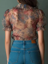 Floral print ruffle trim blouse features ruffled puffed sleeves and cuffs in soft pink blue and beige sheer fabric