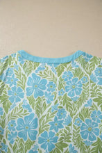 Floral print ruffled color block trim half sleeve blouse in light blue and green with a solid turquoise neckline
